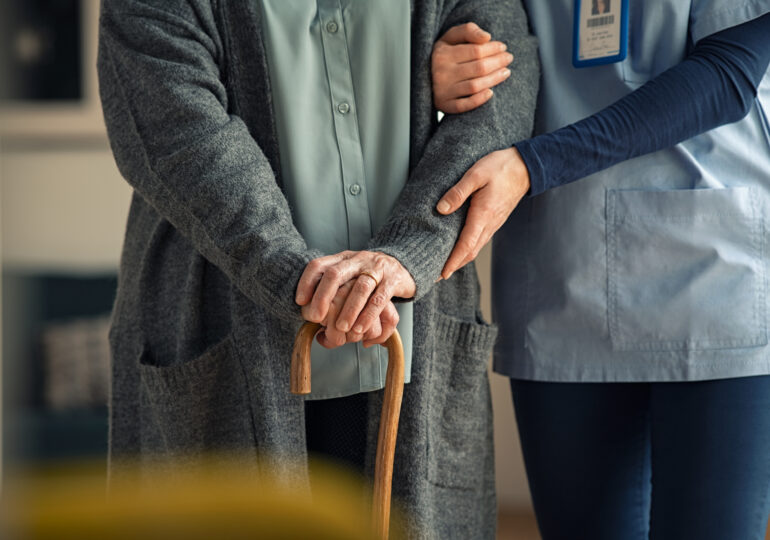 Nurse helping older woman with cane