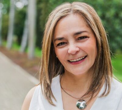 Woman smiling at the camera with beautiful greenery behind
