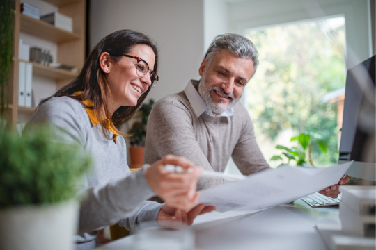 Two adults sitting at desk reviewing paper print out documnts