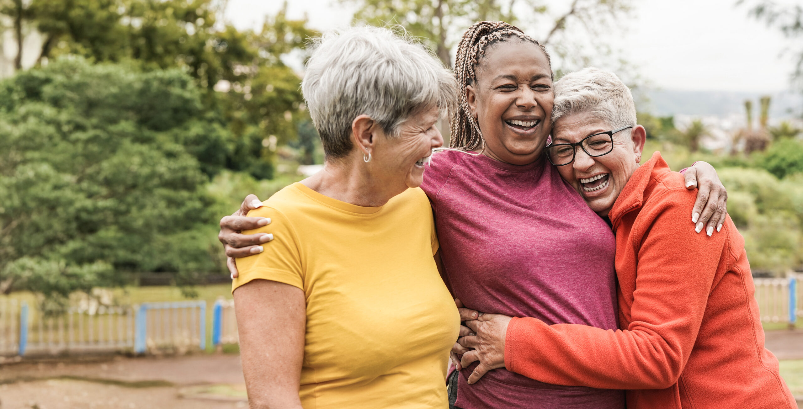 Three women share embrace outside in the sun
